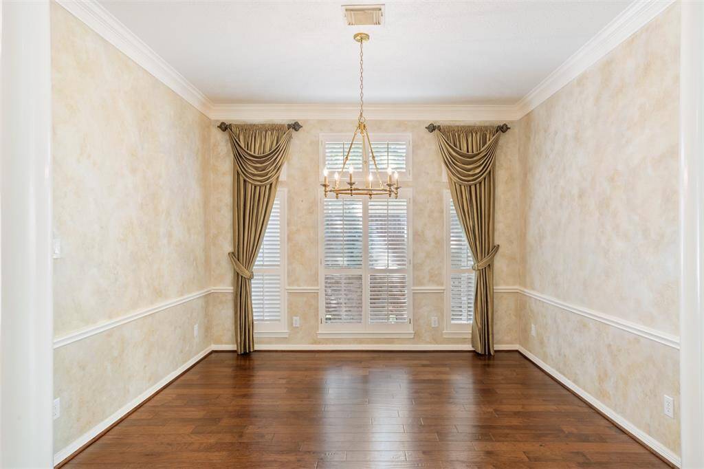 The dining room has been freshly painted in a soft neutral color, and the faux paint shown in this photo is gone.  Valances and drapery have been removed, but the beautiful hardwoods and elegant STIFFEL Chandelier remain to add to the elegance throughout the home.