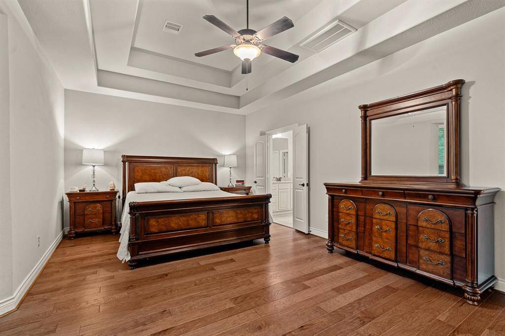 This cozy Primary Bedroom features a high tray ceiling and recently added hardwood floors.