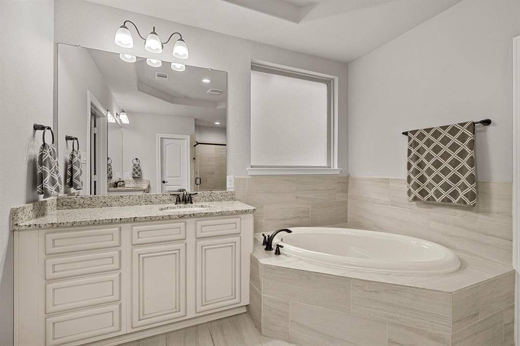 Primary en-suite bathroom boasts two spacious vanities, an inviting corner soaking tub, and a massive double closet.