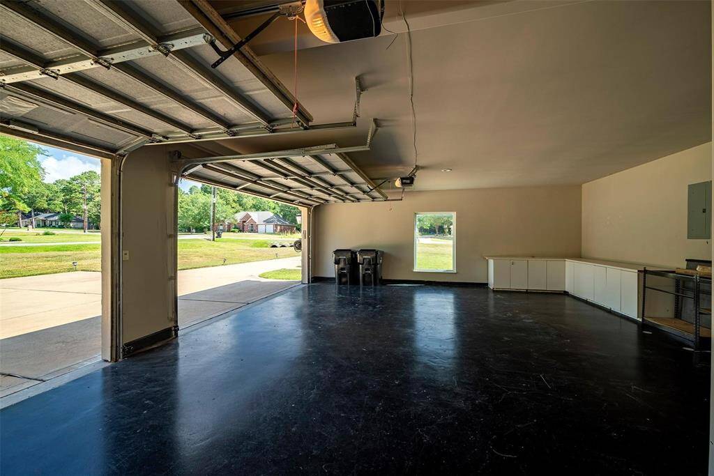 Spacious 3-car garage with polished floors, ample storage cabinets, and a window providing natural light.