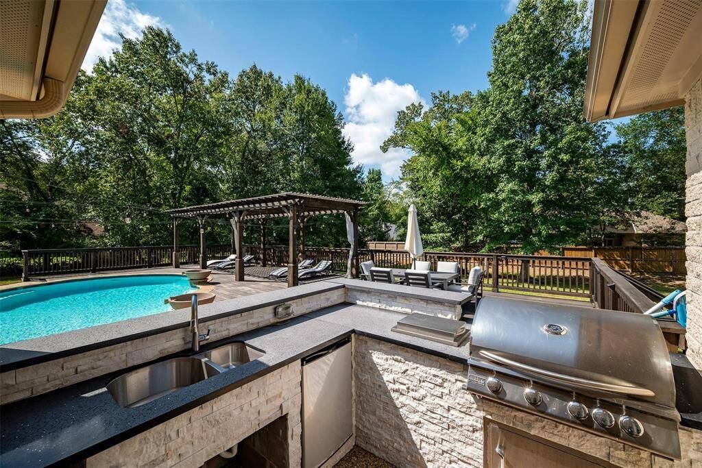There's a built-in outdoor kitchen with a grill and sink, ideal for entertaining. Surrounded by lush trees, it offers a serene and private setting.