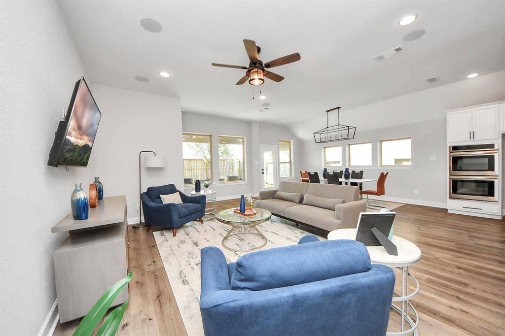 This spacious living room features a ceiling fan and ample natural light from large windows.