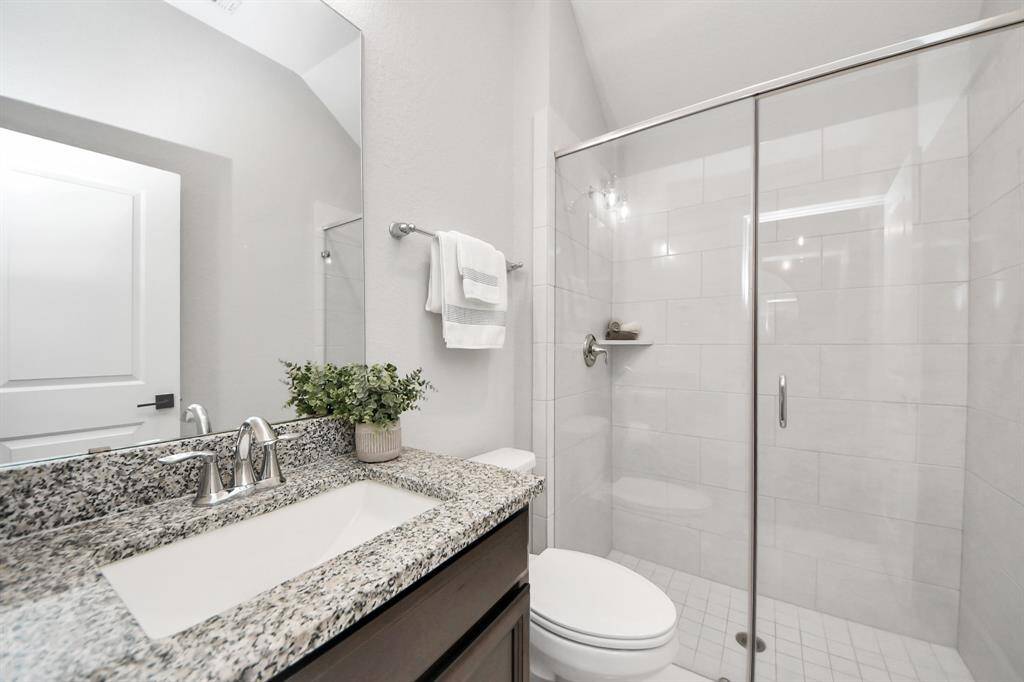 Bathroom features a granite countertop and a sleek stand-up shower for a modern, polished look.