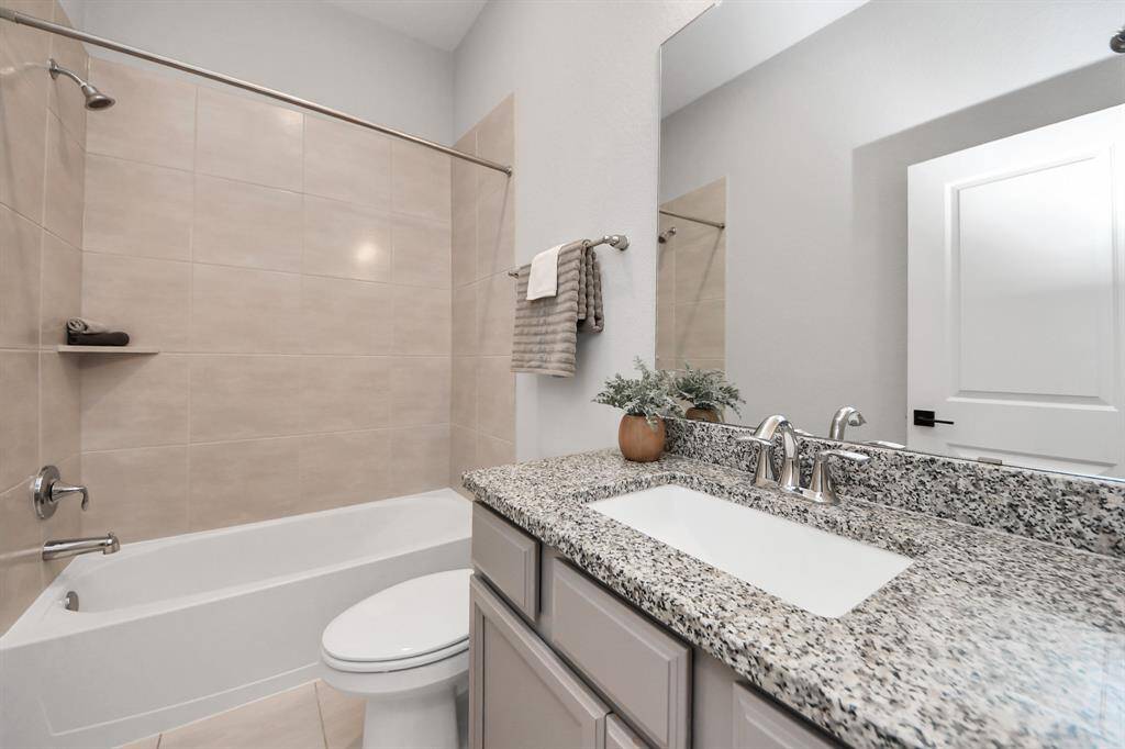 This bathroom features a clean design with a granite countertop, under-mount sink, and chrome fixtures.