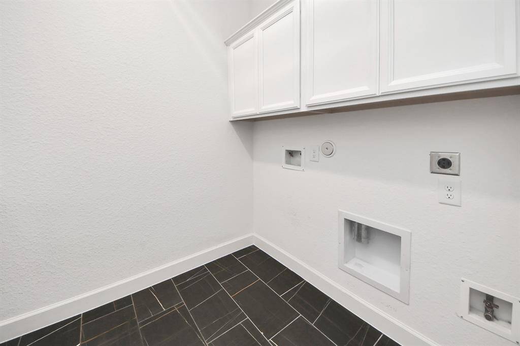 The laundry room is located in the home. The flooring is dark tile, providing a clean and cool look.