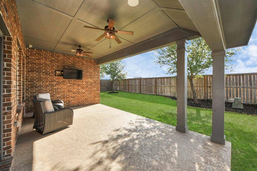 Your outdoor space features a spacious covered patio with ceiling fans, perfect for relaxation or entertaining. It overlooks a well-maintained fenced backyard, offering privacy and a pleasant view.