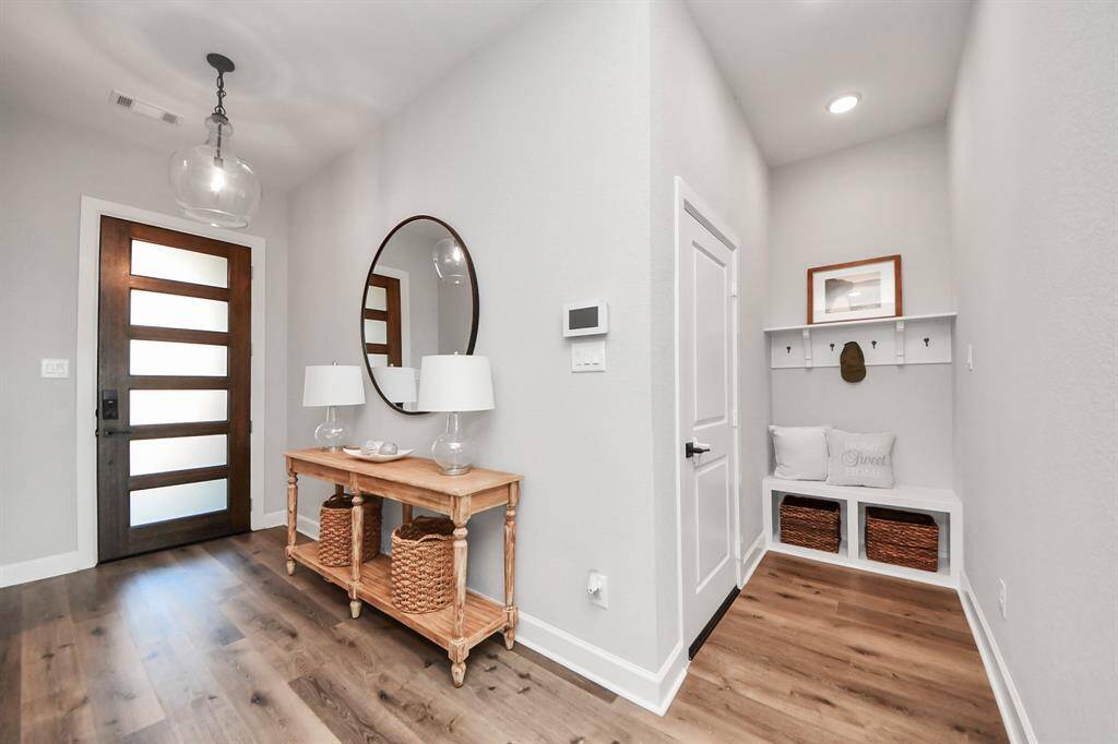 This entryway features a modern wood door with frosted glass, stylish vinyl flooring, and a convenient mud nook.