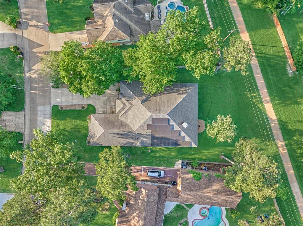 The aerial view highlights the property's serene setting, surrounded by mature shade trees, a lush greenbelt, and a scenic walking path just behind the home. Recently installed in 2023, the solar panels come with a 25-year transferable warranty, offering both energy efficiency and long-term value.