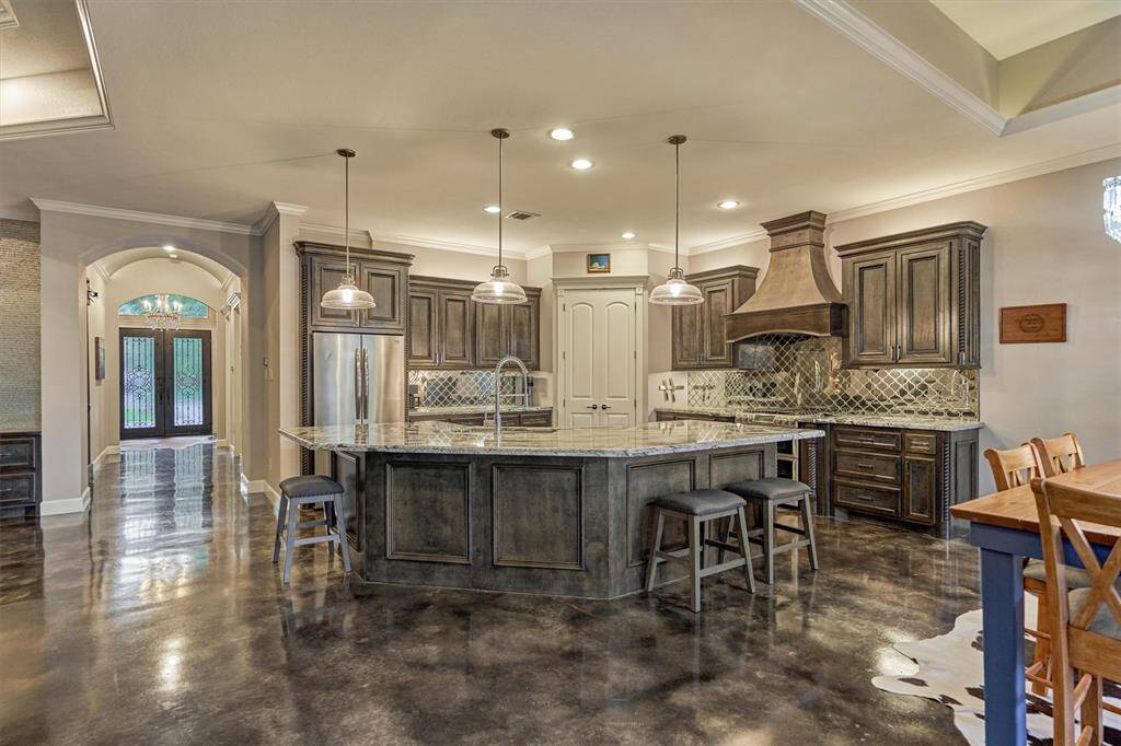 The rich stained cabinetry in the kitchen complements the stained concrete flooring, creating a warm, cohesive look that flows seamlessly throughout the entire home.
