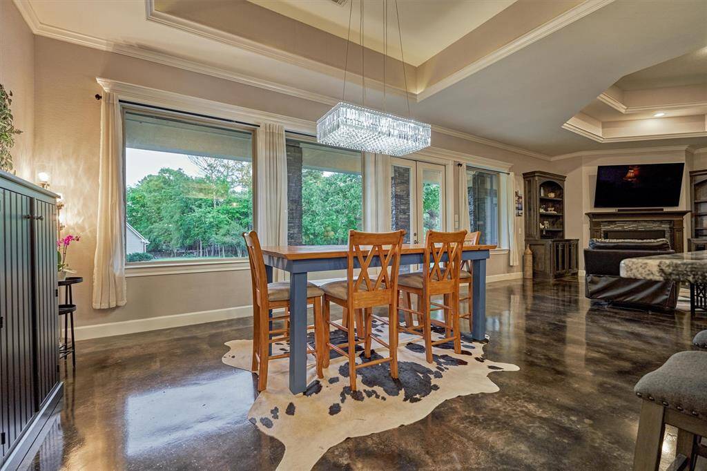 The dining area is elegantly accented by a sparkling crystal chandelier. Tray ceilings enhance the architectural detail and subtly define each space within the open floor plan.