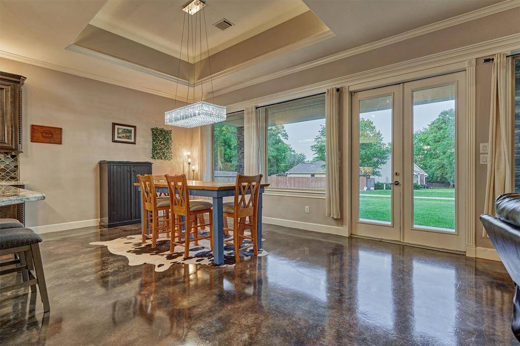 This spacious dining area easily accommodates a larger table for additional seating—perfect for hosting gatherings. Double glass doors open to the covered back porch and fire pit area, extending your entertaining space outdoors.