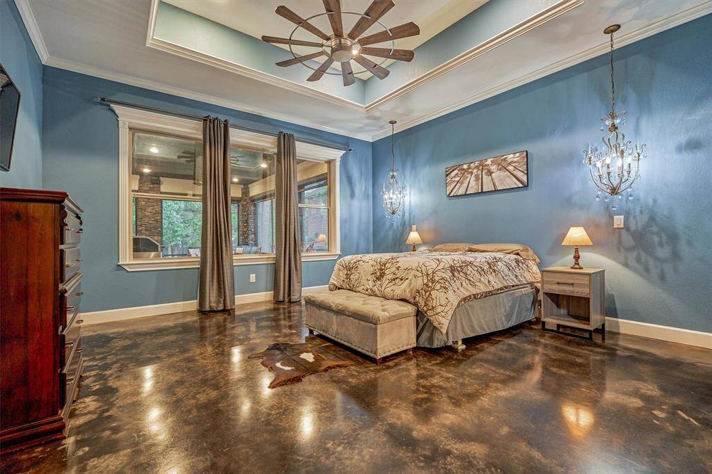 The primary bedroom features a custom ceiling design and elegant crystal chandeliers on either side of the bed, providing sophisticated accent lighting.