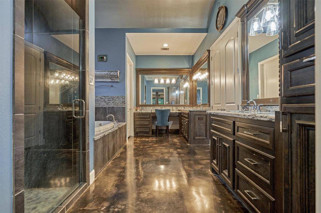 The primary bath offers a luxurious retreat with two separate vanities, each providing ample storage. A jetted soaking tub, separate glass-enclosed shower, private toilet room, and a spacious walk-in closet complete this well-appointed space.