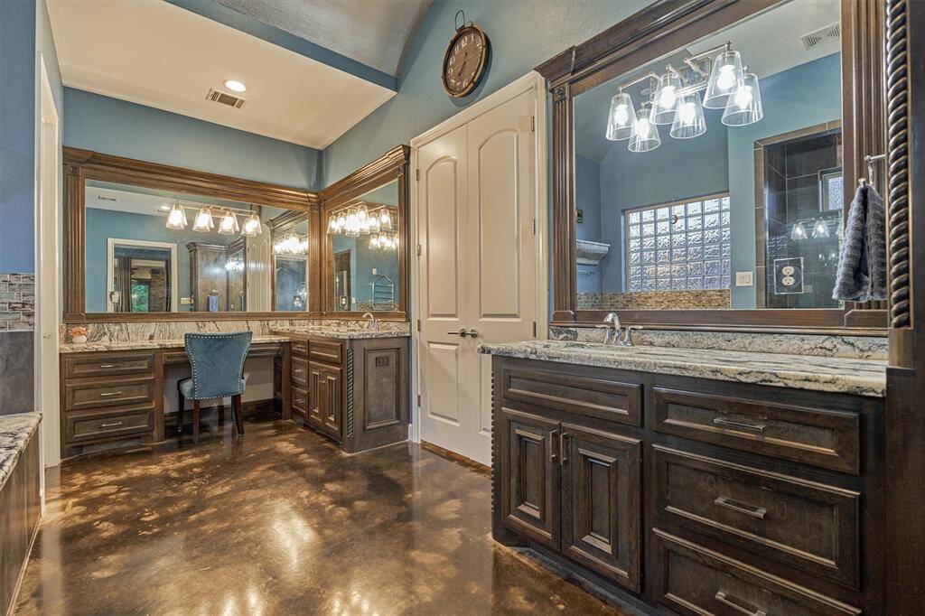 Another view of the dual vanities highlights the framed mirrors, adding a custom, designer touch to the space. A built-in seating area offers a convenient and comfortable spot for getting ready.