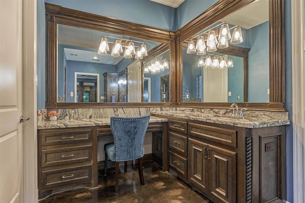 A closer look at the seated vanity area reveals the rich wood cabinetry and the intricate beauty of the granite countertops, highlighting the craftsmanship and attention to detail throughout the space.