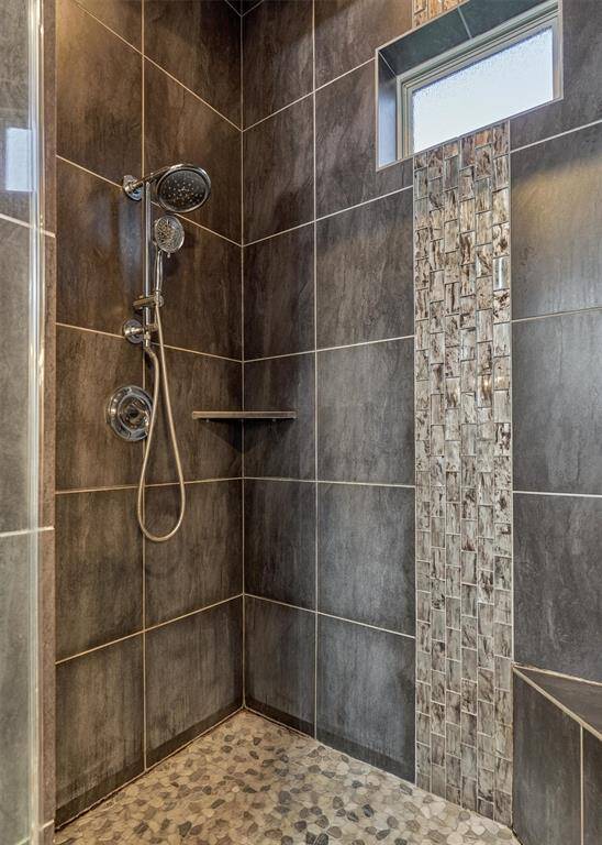 A closer look at the shower reveals thoughtful design elements, including a built-in bench seat, convenient storage shelf, and a striking glass tile accent.