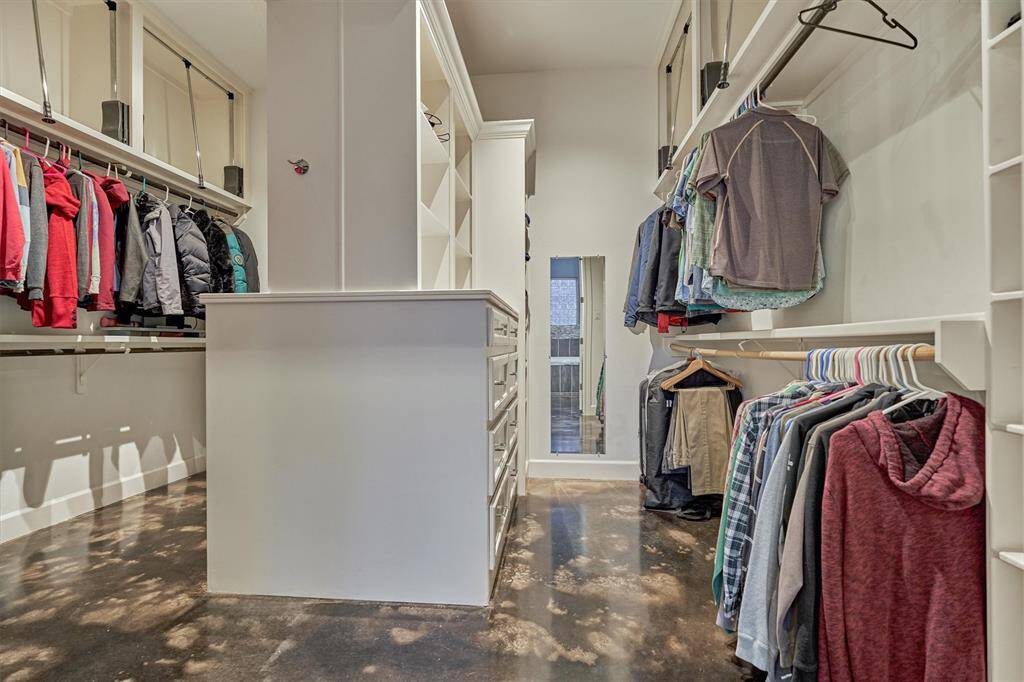 The primary closet is thoughtfully designed with dual sides, providing separate areas for enhanced privacy and convenience. Featuring a smart combination of open shelving, built-in drawers, and pull-down rods on the upper levels, this space is optimized for maximum storage and effortless organization.