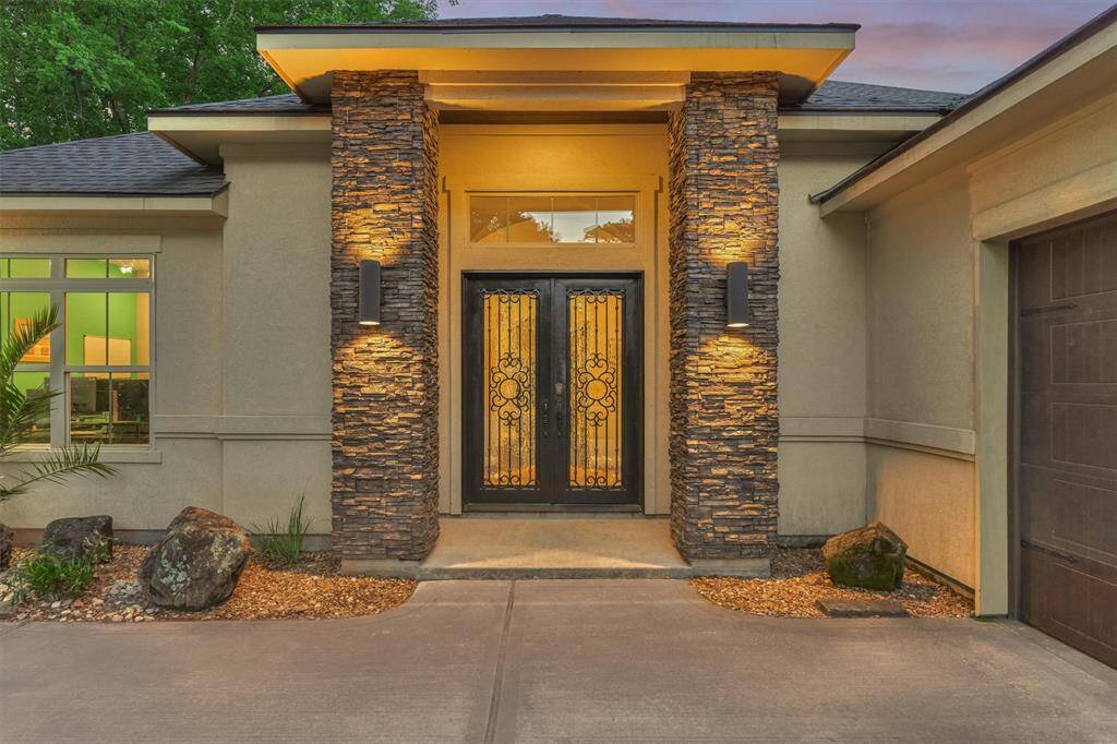 The covered entry is elegantly framed by stacked stone columns and modern lighting, offering a stylish and welcoming first impression.