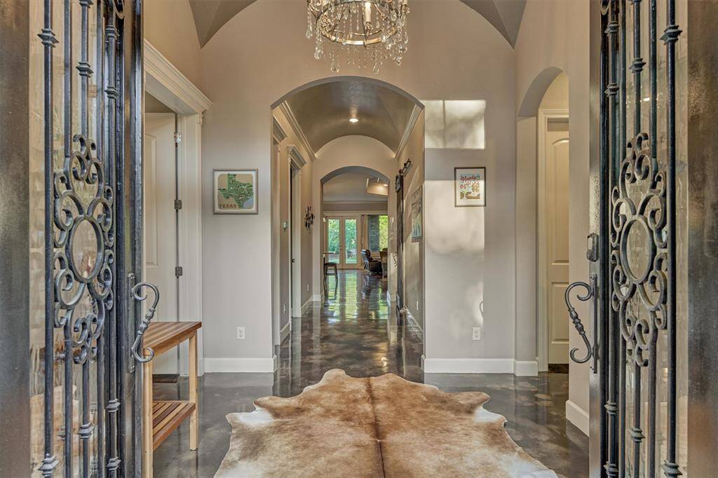 Step into the beautiful entry foyer, featuring a stunning crystal chandelier and a custom groin-vaulted ceiling finished in a soft pearl shimmer.