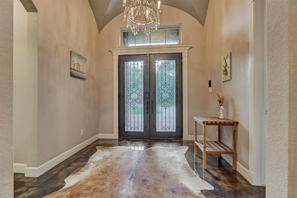 This view shows the rich wood-stained double glass doors, beautifully detailed with wrought iron accents that add a touch of timeless elegance and character to the entry.