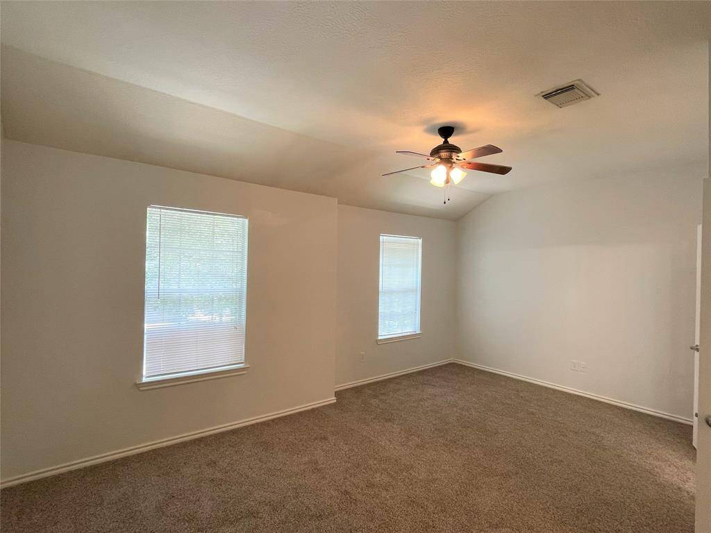 Spacious primary bedroom with abundant natural light and a ceiling fan for comfort.