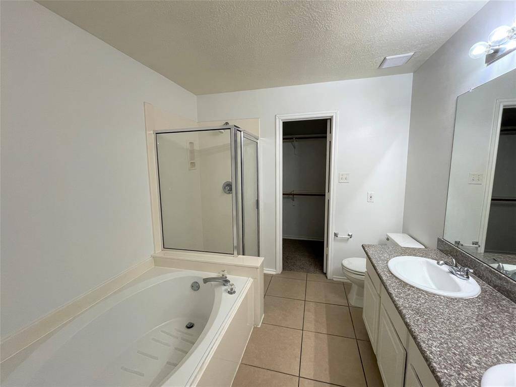 This bathroom features a spacious layout with a large soaking tub and separate shower. a walk-in closet.