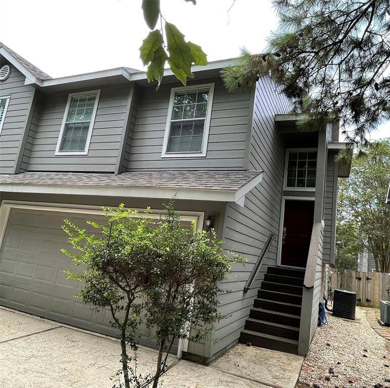modern, two-story home with a gray exterior and a two-car garage. A staircase leads up to the main entrance,