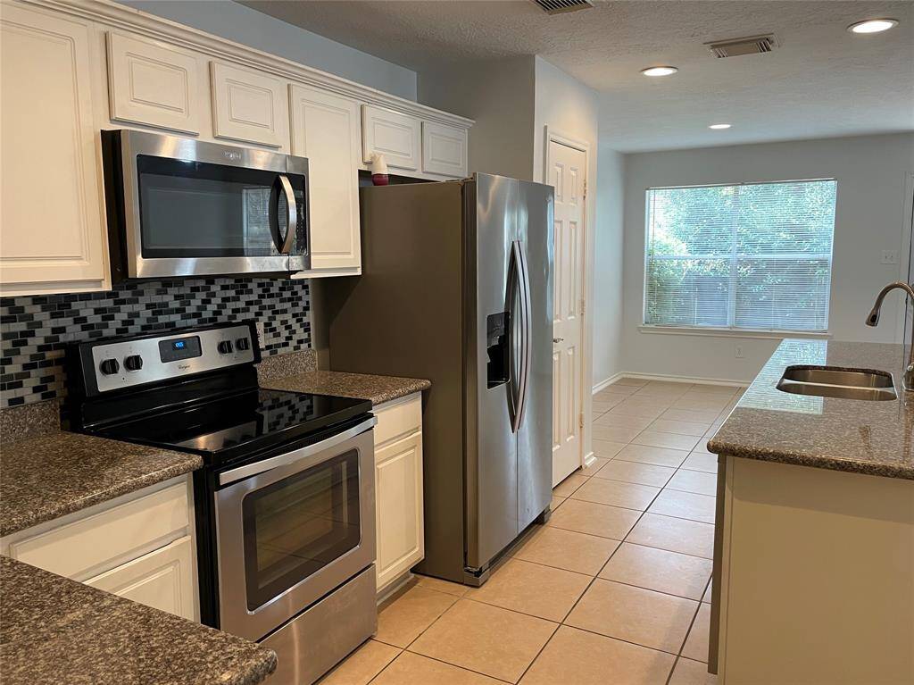 Modern kitchen with sleek stainless steel appliances, stylish backsplash, and ample natural light.