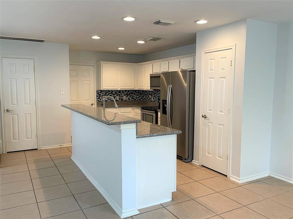 Modern kitchen with sleek granite countertops, stainless steel appliances, and ample cabinet space. Features a stylish tile backsplash and recessed lighting, offering a clean and contemporary look.