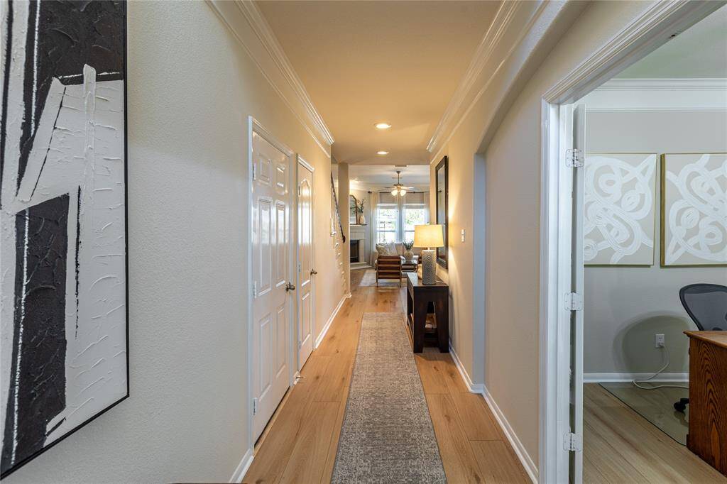 Foyer trimmed with crown molding, wide plank floors and soothing paint color