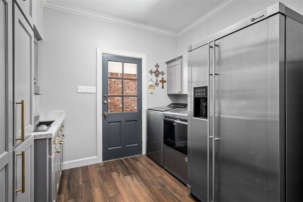 Laundry room with sink is conveniently located near the kitchen. Custom cabinets offer great storage. Door leads to the breezeway between the house and 3-car garage.