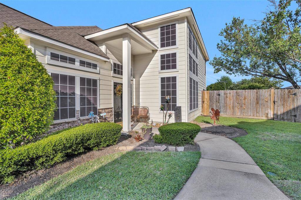 Modern home exterior featuring large windows, a welcoming front porch, and well-maintained landscaping with lush shrubs and a curved walkway. ***see 2nd gate that leads to HOA reserve****