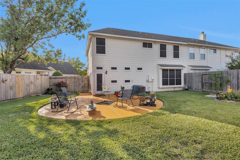 A spacious backyard with a well-maintained lawn and a circular patio area featuring outdoor seating. Fully wooden fence, offering privacy and a cozy outdoor space for relaxation or entertaining.