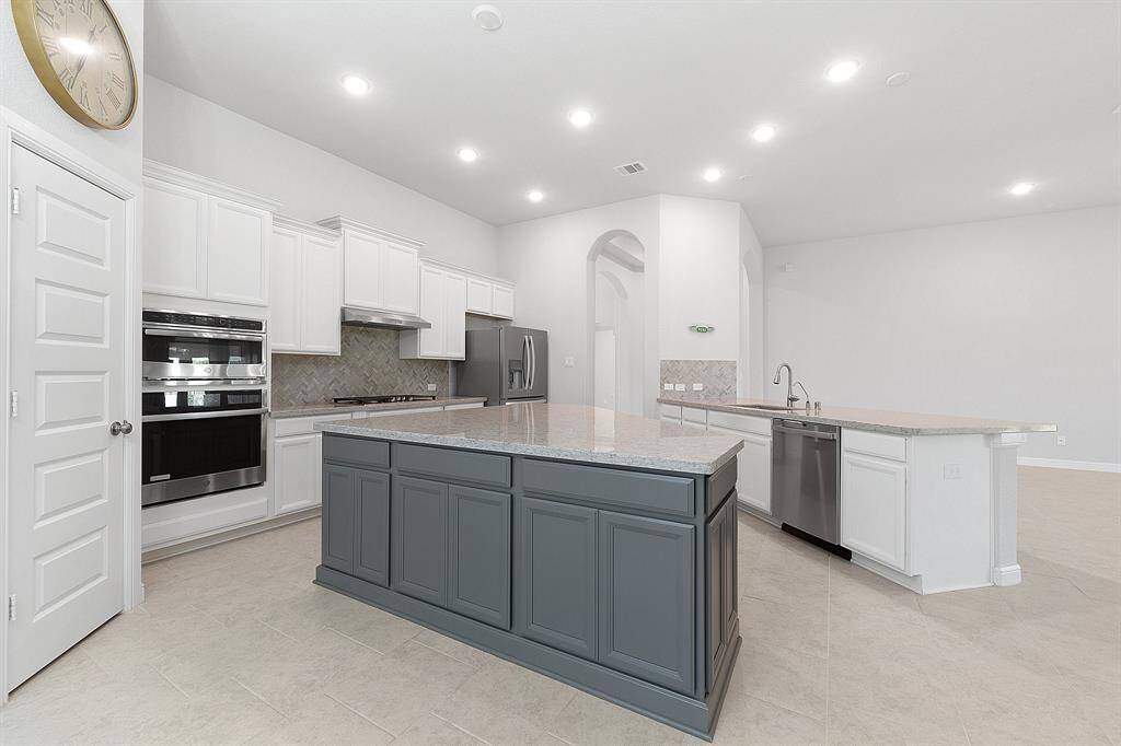 Gourmet kitchen boasts a striking two-tone island, stainless steel appliances, and generous storage. The oversized island is perfect for hosting or gathering with family.
