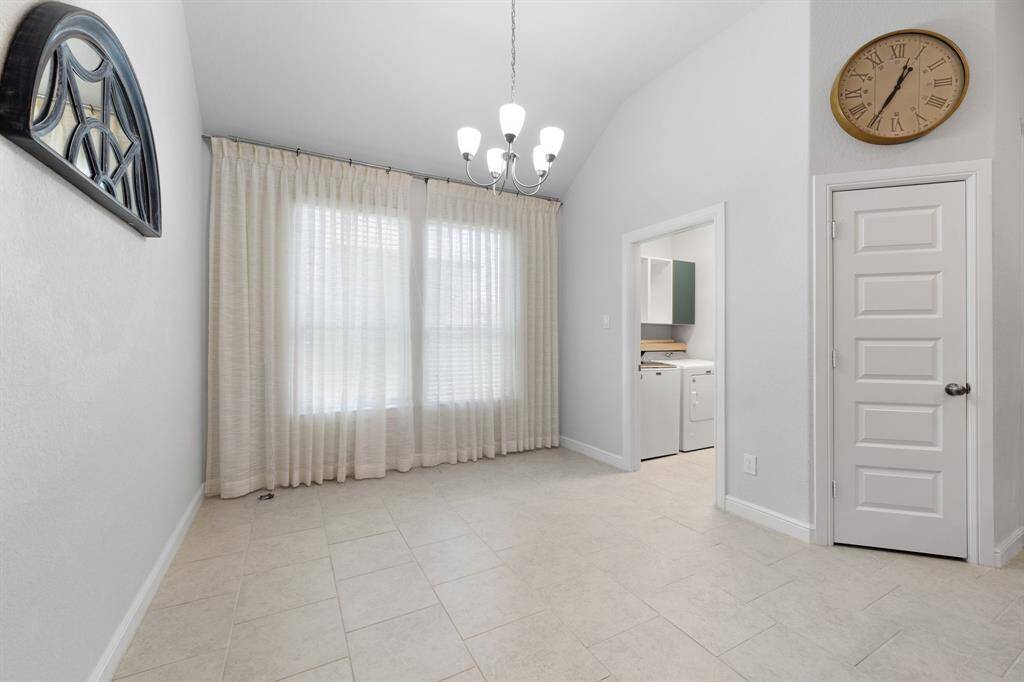 Cozy dining area with high ceilings, natural light, and direct access to the laundry room—convenient and inviting for everyday meals.