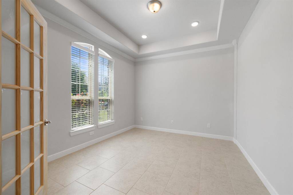Bright and versatile study with tray ceiling, recessed lighting, and elegant French doors—perfect for a home office or reading room.