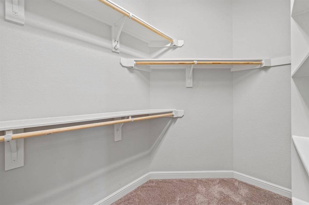 The spacious walk-in closet offers double-tier hanging space and built-in shelving for optimal organization.