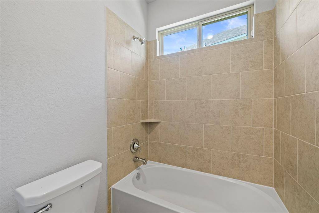 Secondary bath with a tiled shower/tub combo and upper privacy window allowing natural light while maintaining privacy.