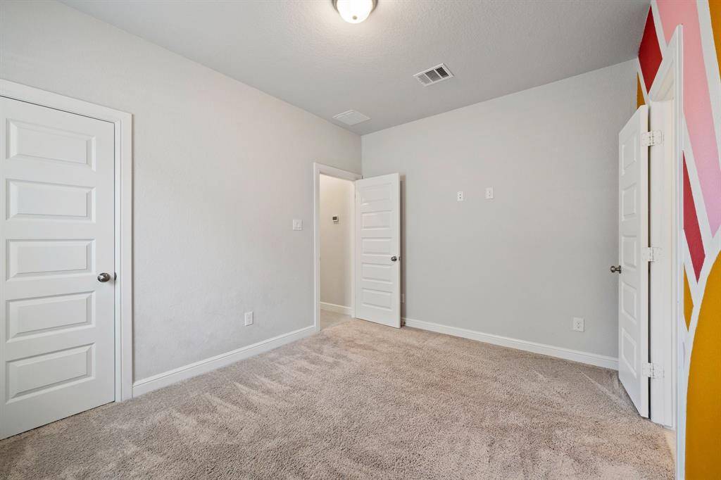 Natural light streams in through the window, accentuating the cheerful color palette and cozy carpet.