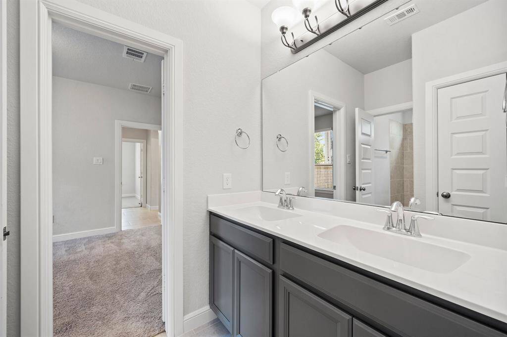 Stylish secondary bathroom with dual sinks, modern lighting, and direct access to adjacent bedrooms—ideal for shared living.