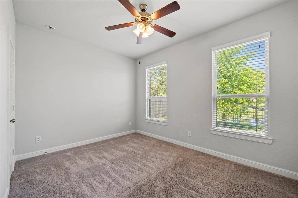Sunlit secondary bedroom with plush carpet, dual windows, and a ceiling fan for added comfort and airflow.