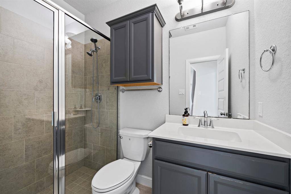 Elegant full bathroom featuring a glass-enclosed walk-in shower, sleek tilework, and an overhead cabinet for extra storage.