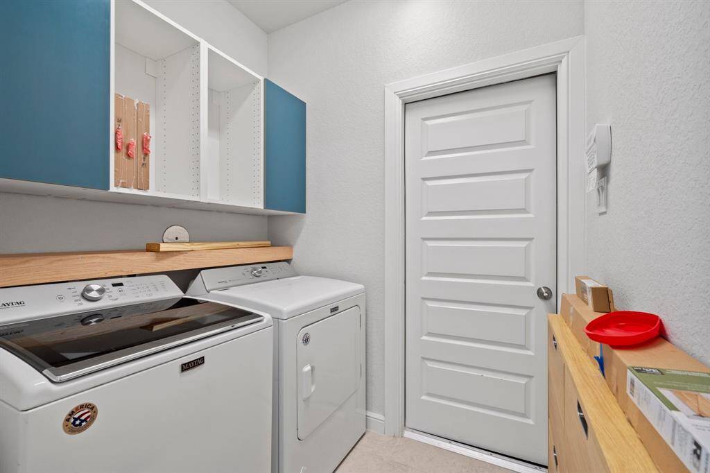 Dedicated laundry space with built-in upper cabinetry and access to the garage for added convenience.