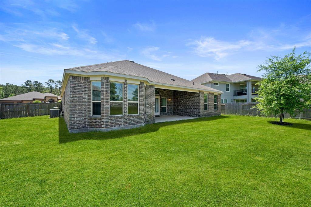 The expansive backyard offers plenty of green space, while the home’s rear elevation features beautiful brickwork and large windows for abundant natural light.