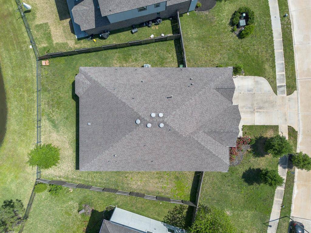 Aerial view showcases the expansive roofline, large backyard, and private driveway of this well-maintained home on a generously sized lot.