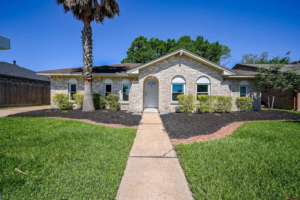 This charming single-story home features a light brick exterior, arched windows, and a welcoming front path. It boasts well-maintained landscaping with a palm tree and lush green lawn, offering excellent curb appeal.