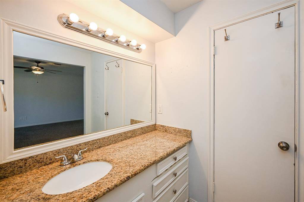 Primary bathroom vanity with sleek granite countertop, ample storage, and elegant lighting.
