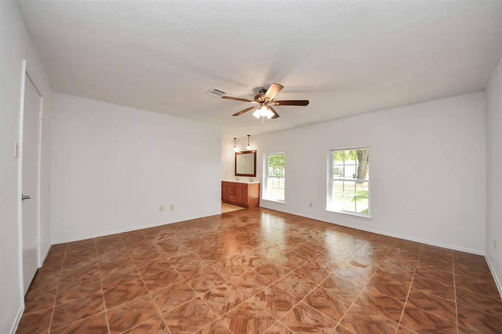 The primary bedroom boasts an ensuite bath, tile flooring, a walk-in closet, two windows for natural light, and a ceiling fan.