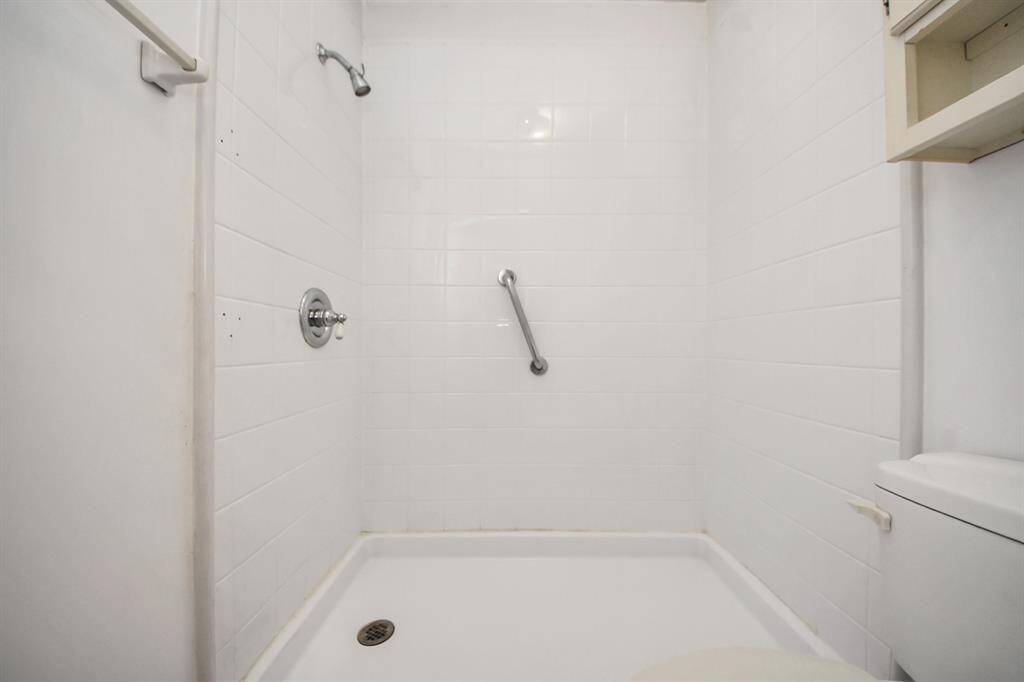 The primary bathroom features a stand-up shower with floor-to-ceiling tile and convenient storage above the toilet.