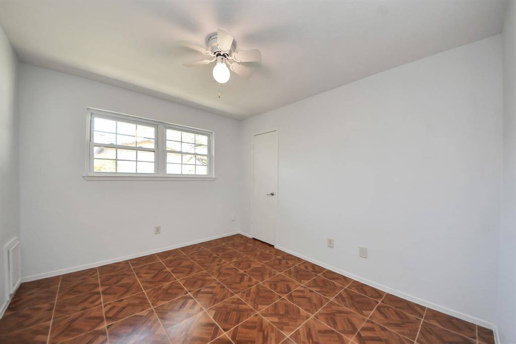 Bedroom 1 features tile flooring, a ceiling fan for added comfort, and a spacious walk-in closet.